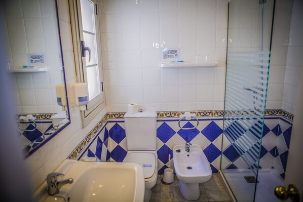 Un baño con inodoro, bidé, lavabo y ducha.