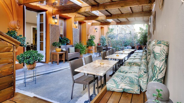 Une terrasse extérieure avec des tables et des chaises en bois, un canapé et des plantes en pot.
