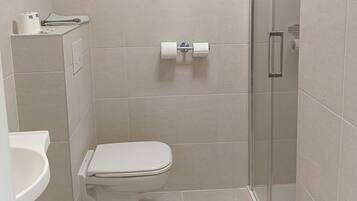 A bathroom with a toilet, a sink, and a shower stall.