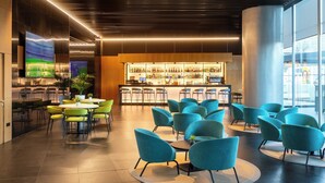A modern bar area with seating and a large TV screen. - Alexandre Fira Congress (L'Hospitalet de Llobregat)