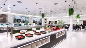 A modern, well-lit buffet area with various food stations, including bowls of fruits and vegetables, and a glass display case. - Alexandre Fira Congress (L'Hospitalet de Llobregat)