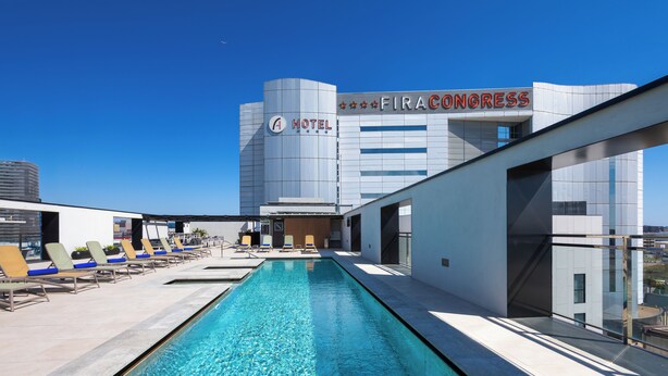 A hotel with a rooftop pool, lounge chairs, and a view of the Fira Congress building. - Alexandre Fira Congress (L'Hospitalet de Llobregat)