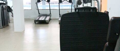 A gym with treadmills, weight machines, and a large window.