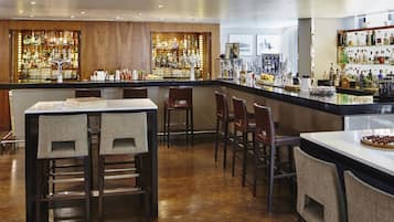 A bar area with wooden paneling, a variety of liquor bottles, and bar stools.
