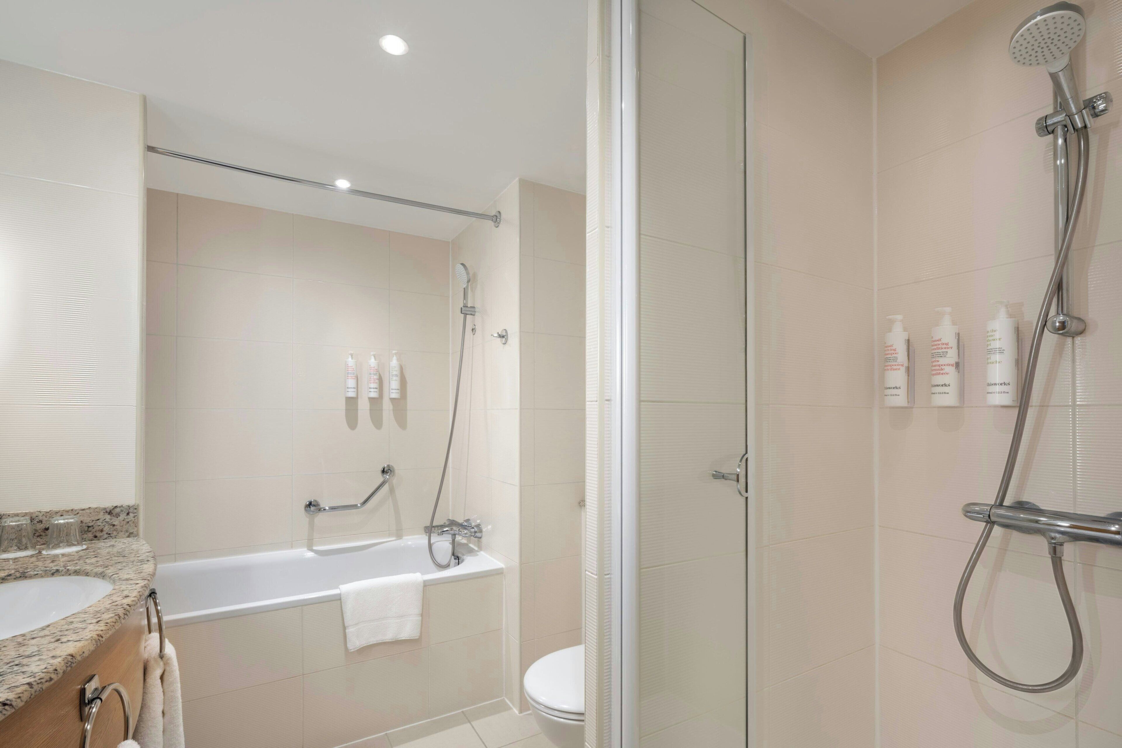 Een moderne badkamer met een bad, douche en toilet.