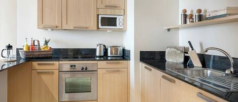 A modern kitchen with wooden cabinets, a microwave, a stove, and a sink.