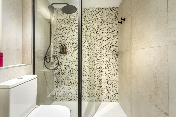 A bathroom with a glass shower enclosure, a toilet, and a sink. - Vibra Vila New Opening 2026 (Ibiza Town)