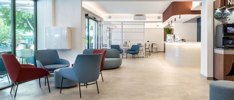 Un moderno vestíbulo de hotel con zonas de estar, una recepción y un amplio ventanal con vistas al exterior.