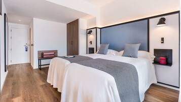 Una camera d'albergo moderna con un ampio letto, comodini, un armadio e una piccola area salotto.