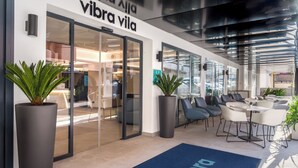 Un interior moderno con una zona de recepción, asientos y una gran planta en maceta.