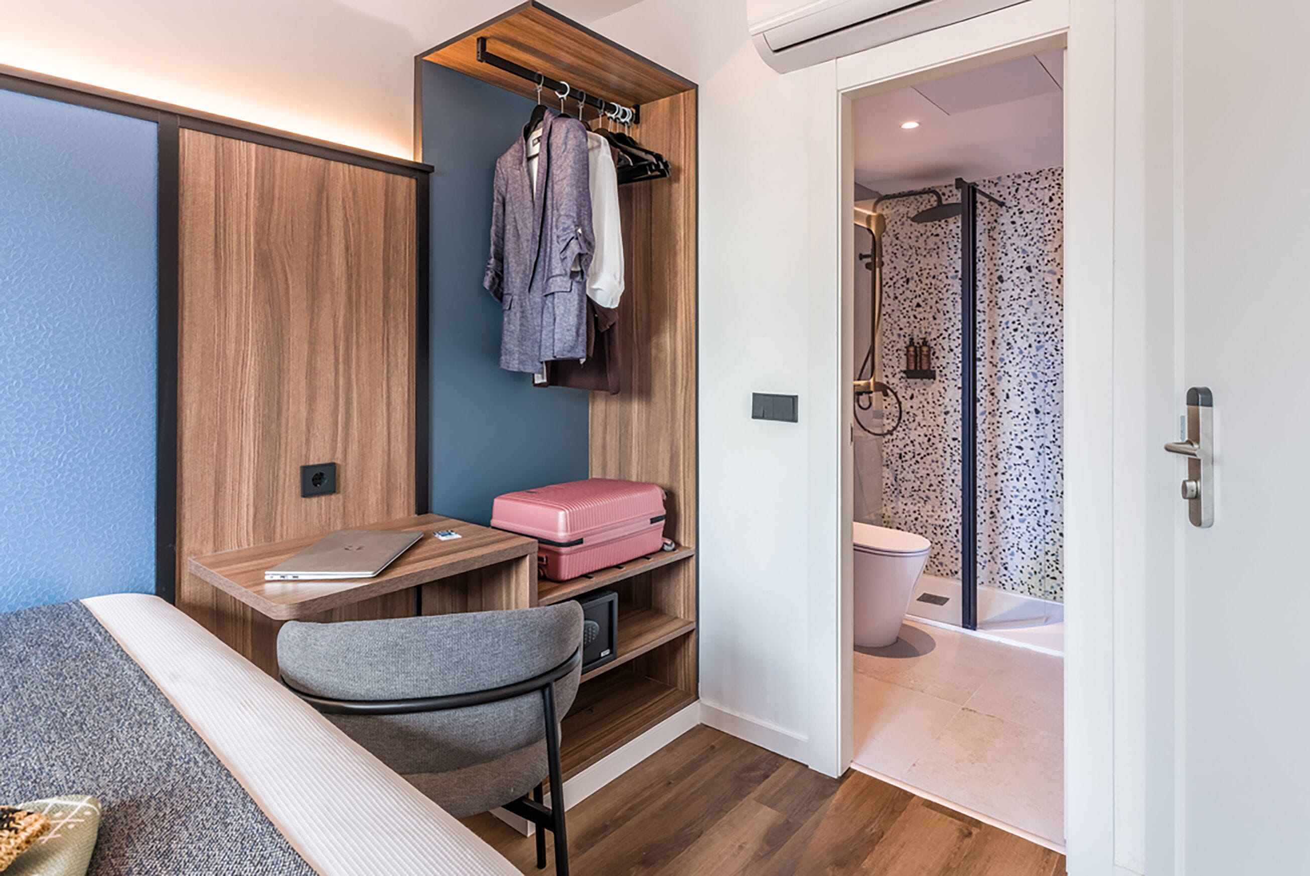 A compact room with a desk, chair, and a small seating area.