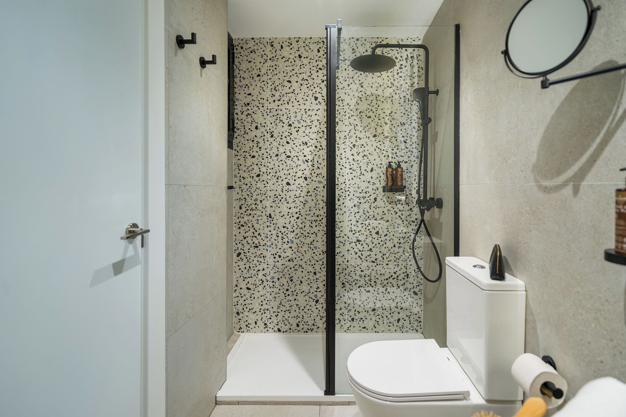 Un baño moderno con ducha, inodoro y espejo.