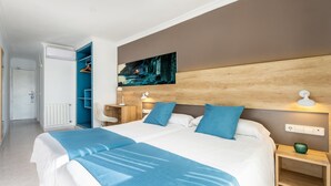 A modern hotel room with a large bed, a wooden headboard, a painting above the bed, and a walk-in closet with blue shelving. - Hotel Vibra Maritimo (Ibiza Town)