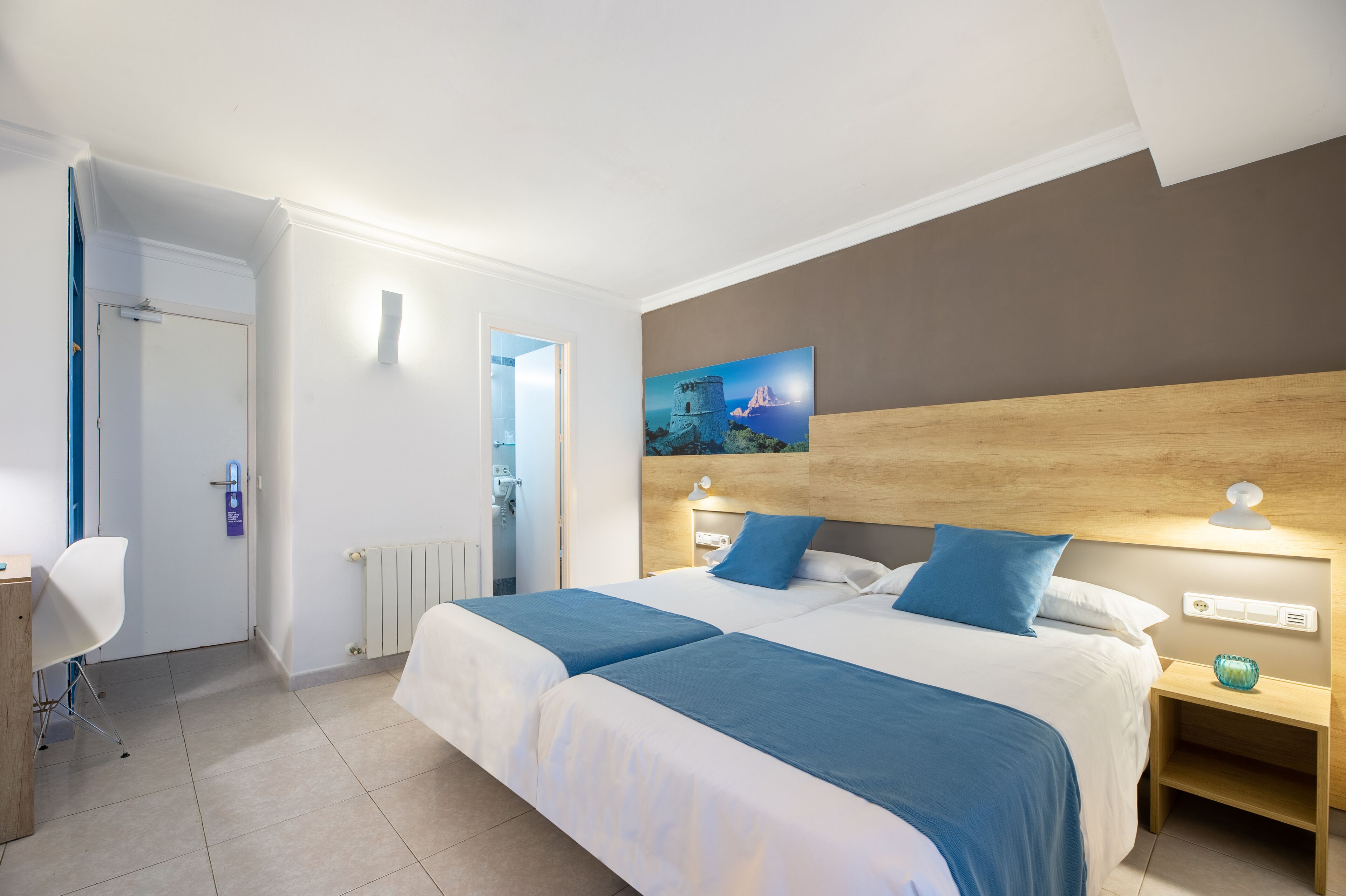 A hotel room with a large bed, bedside tables, a desk, and a chair.