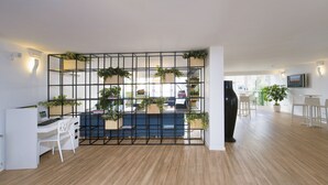 Un espacio de oficina moderno con suelo de madera, mobiliario blanco y un jarrón decorativo negro.