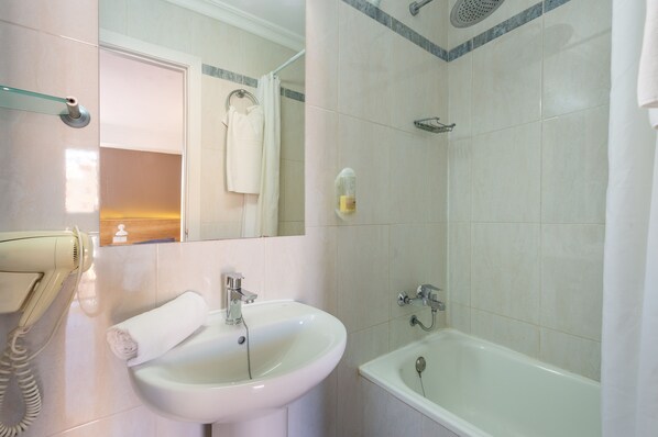 Baño con lavamanos, espejo, toallero, ducha y secador de pelo.