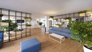 Un interior moderno con un sofá azul, una mesa de centro blanca y piso de madera.