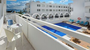 Une piscine sur le toit offrant une vue dégagée sur la mer et les bâtiments blancs, ainsi qu’un panneau indiquant qu’il est interdit de se garer.