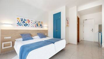 A bedroom with a bed, a blue door, and a wall-mounted artwork.