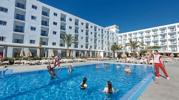 Zona de piscina con varios niveles de balcones, tumbonas y palmeras.