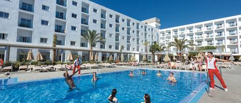 A swimming pool area with multiple levels of balconies, sun loungers, and palm trees.