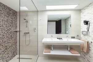 Een moderne badkamer met een douchecabine van glas, een wit wastafelmeubel en een grote spiegel.