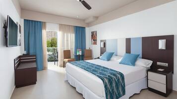A hotel room with a bed, a desk, a chair, a TV, and a balcony with curtains.