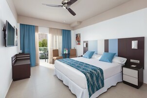 A hotel room with a bed, a desk, a chair, a TV, and a balcony with curtains.