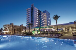 A hotel with a pool, outdoor seating, and a modern building with balconies.