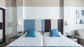 Une chambre d’hôtel avec un grand lit, deux oreillers, une table de chevet, une lampe et une chaise.