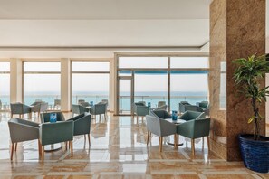 A spacious indoor area with multiple seating arrangements and large windows offering a view of the sea. - Hotel Best Benalmádena (Benalmádena)