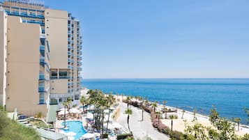 A hotel with a pool, beach, and ocean view.