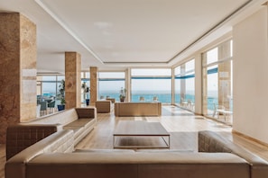 A spacious living area with a large window overlooking the sea, a seating area with sofas, and a view of the ocean. - Hotel Best Benalmádena (Benalmádena)