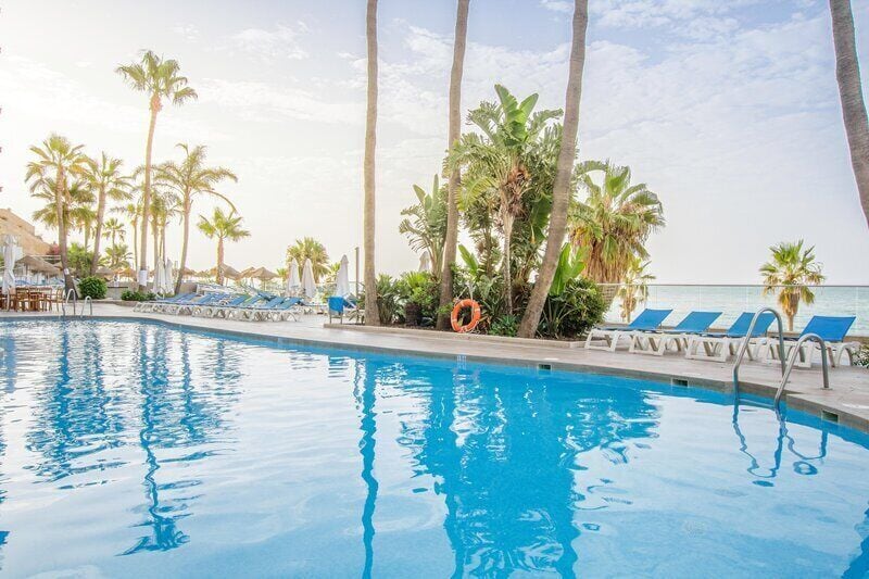Una piscina al aire libre, sombrillas, tumbonas