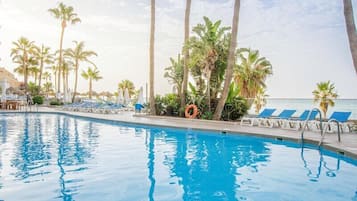 Una piscina al aire libre, sombrillas, tumbonas