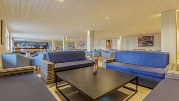 Un espace lounge moderne avec des canapés et une table basse, un bar à l’arrière-plan et un plafond orné d’un motif original.