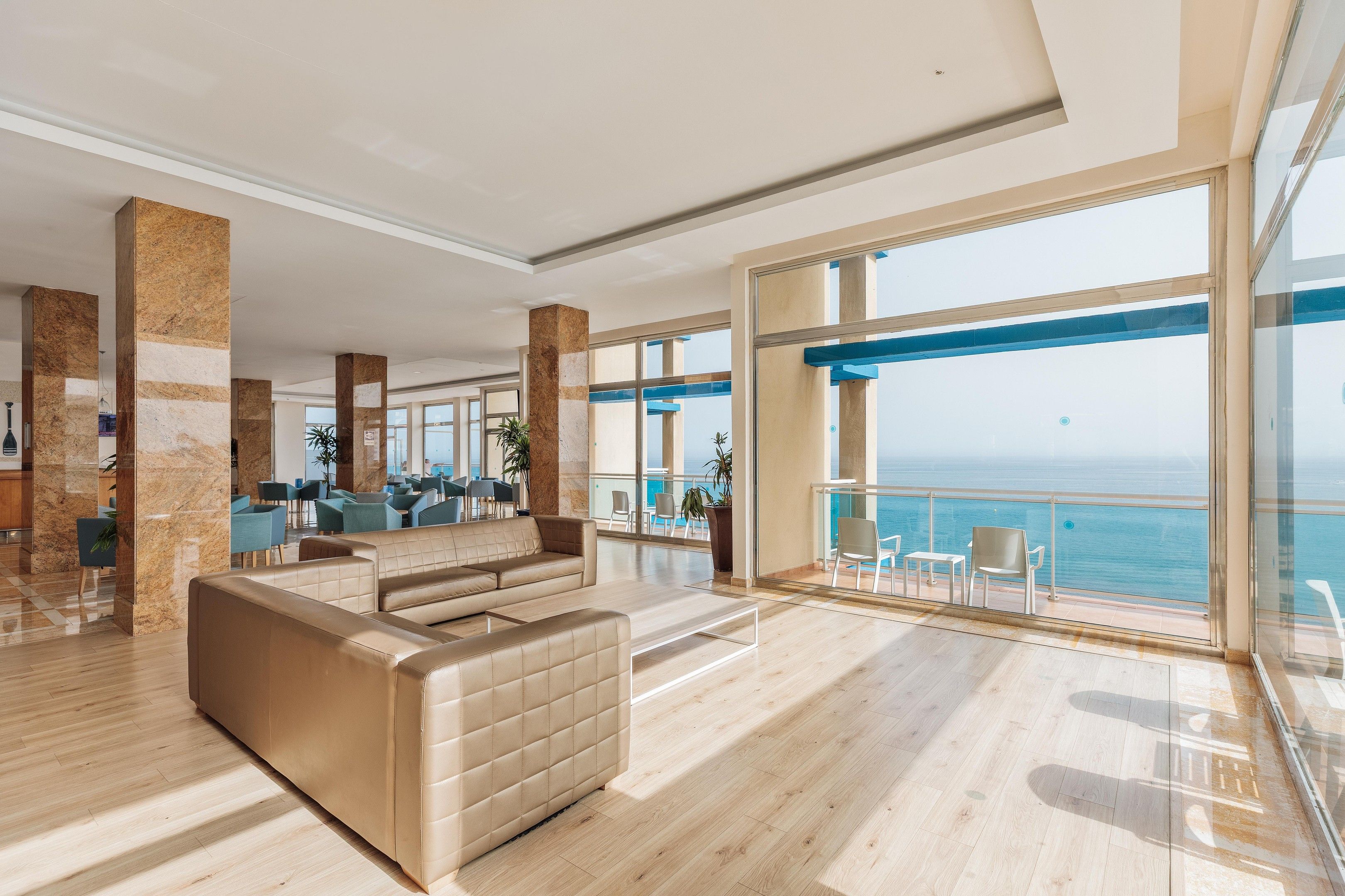 Un vestíbulo amplio con zona de estar, ventanas grandes y vista al mar.