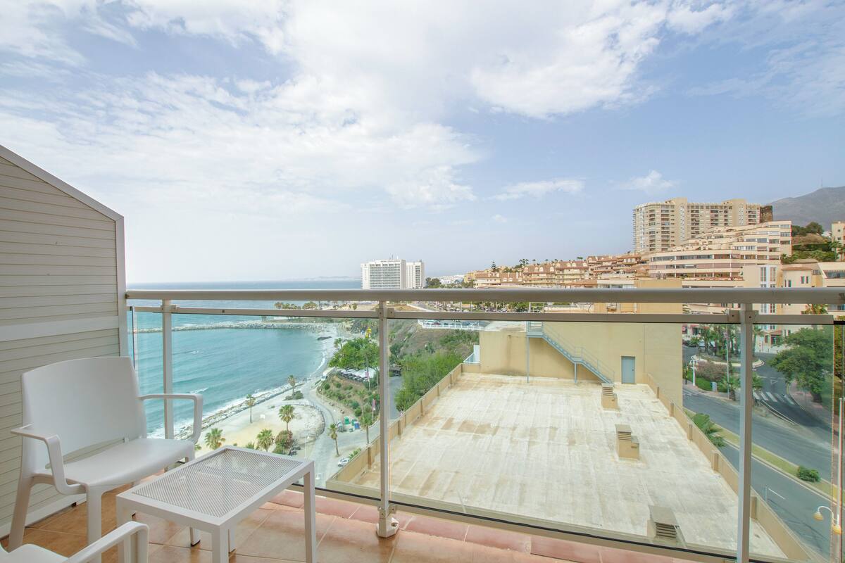 Un balcon avec vue sur l’océan et sur le paysage urbain.