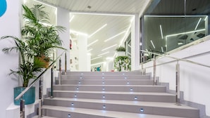A modern staircase with integrated lighting, surrounded by white walls and potted plants. - Hotel Caserío (San Bartolomé de Tirajana)