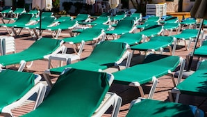 Rows of white lounge chairs with green covers, arranged on a brick patio. - Apartamentos Las Faluas (San Bartolomé de Tirajana)