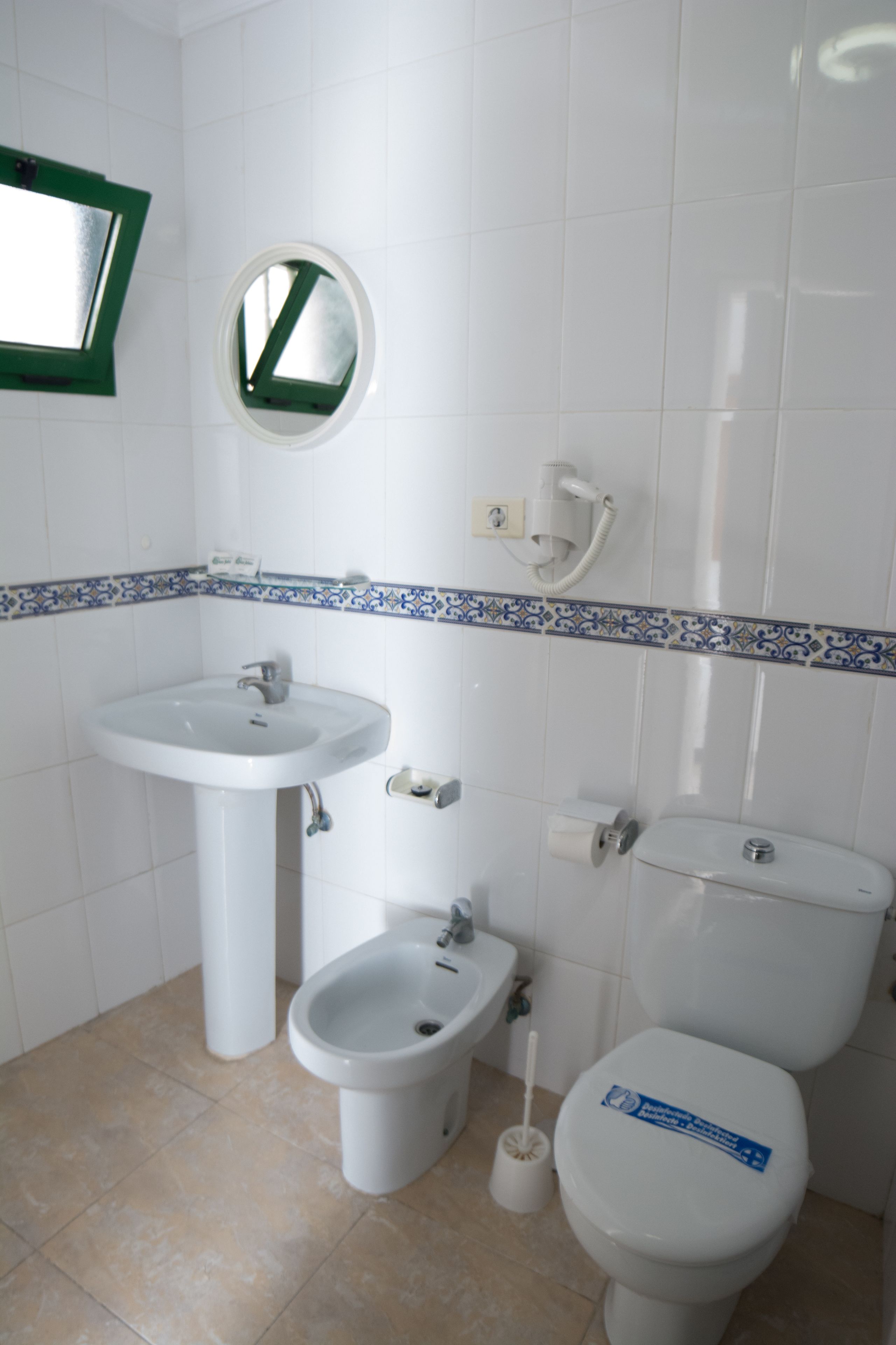 Un baño con lavamanos pedestal, un bidé y un inodoro.