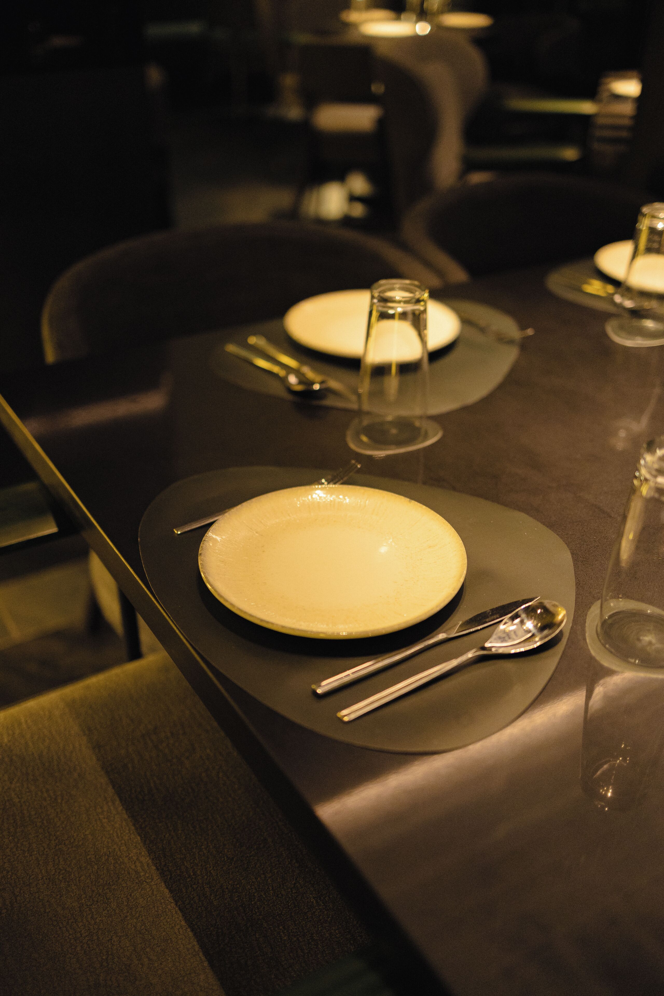 A dining table set with plates, cutlery, and glasses, suggesting a formal dining arrangement.