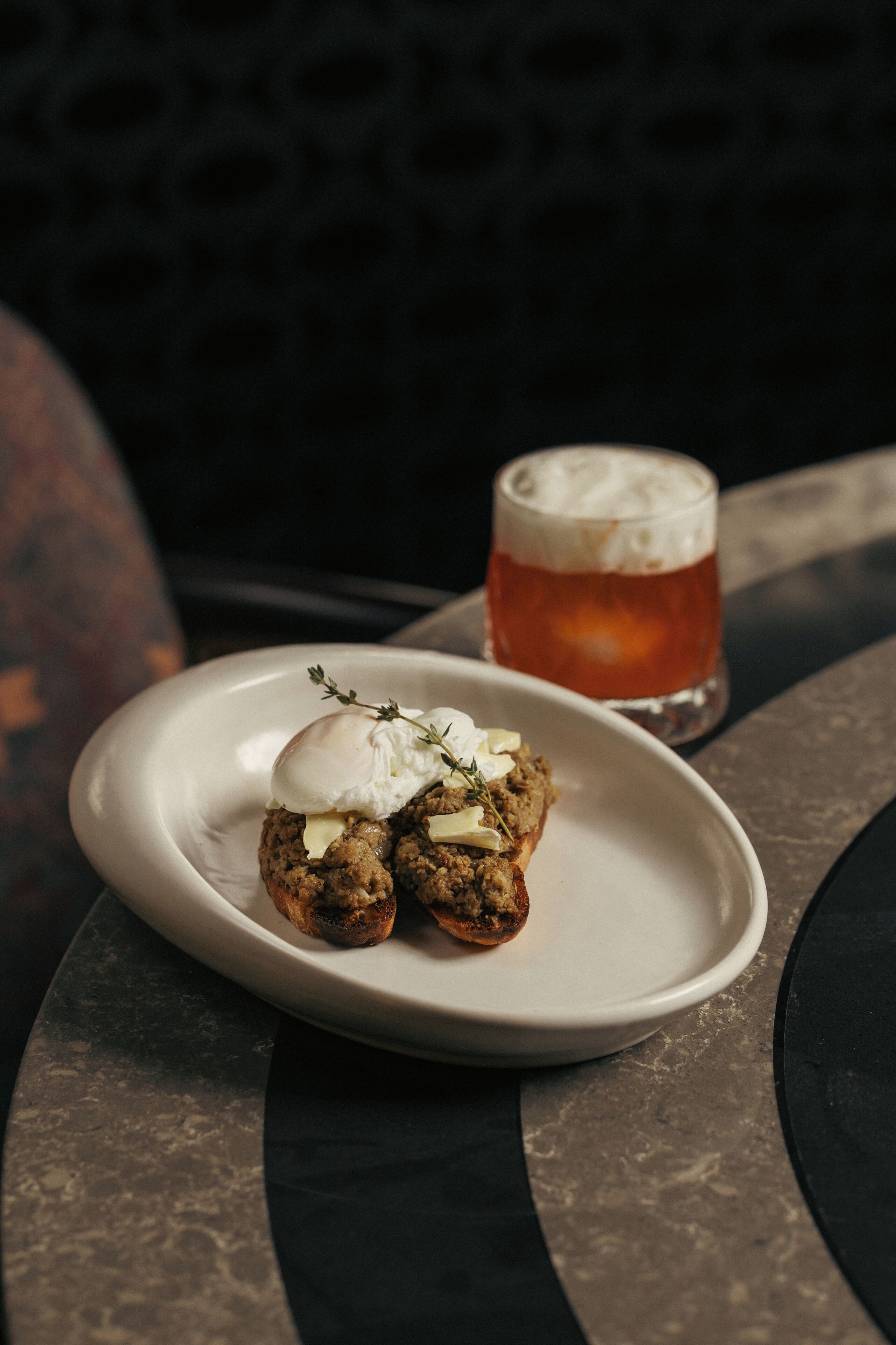 A plate with food and a glass of beer on a table.