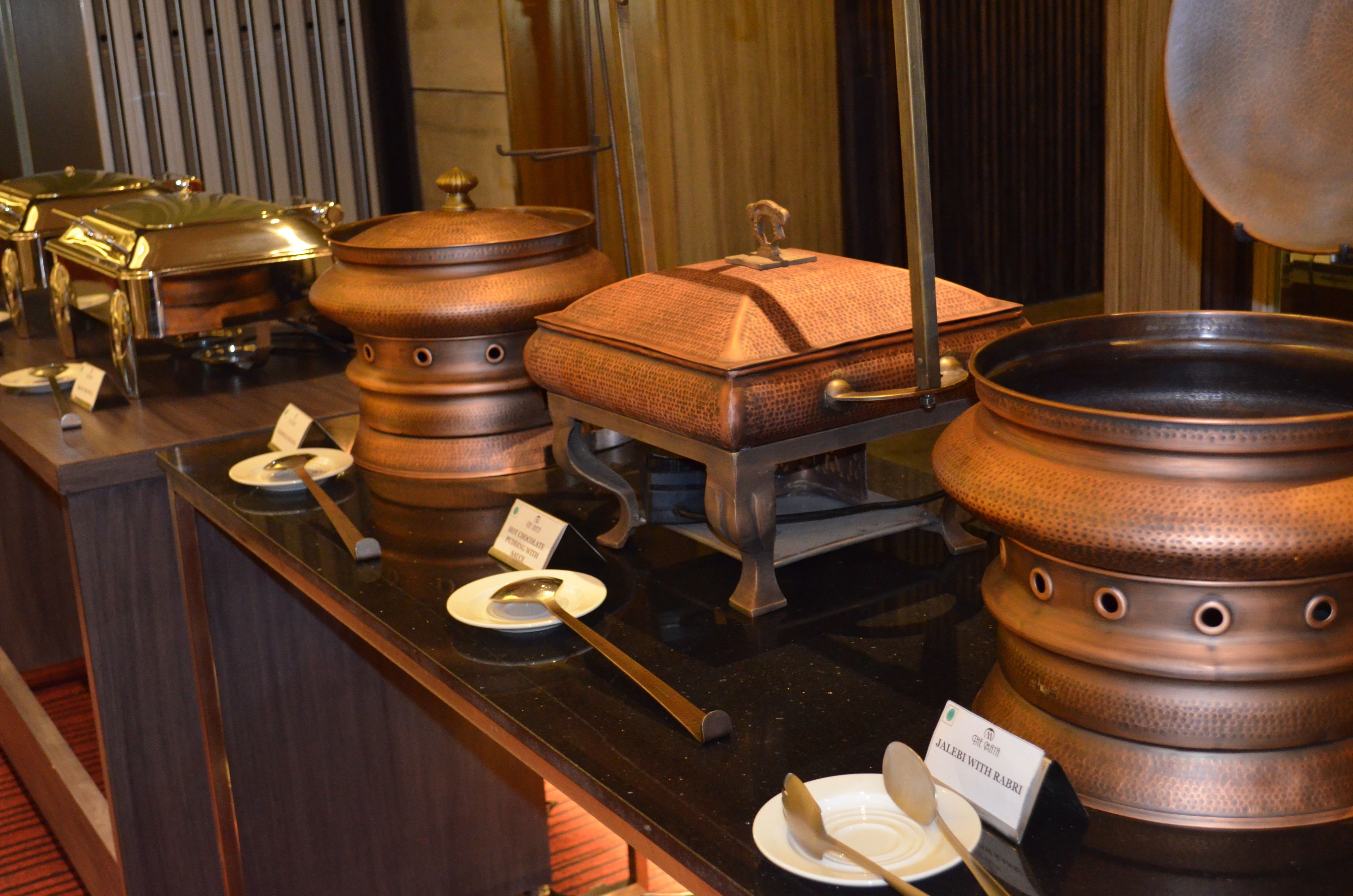 A buffet setup with various food containers and serving utensils.