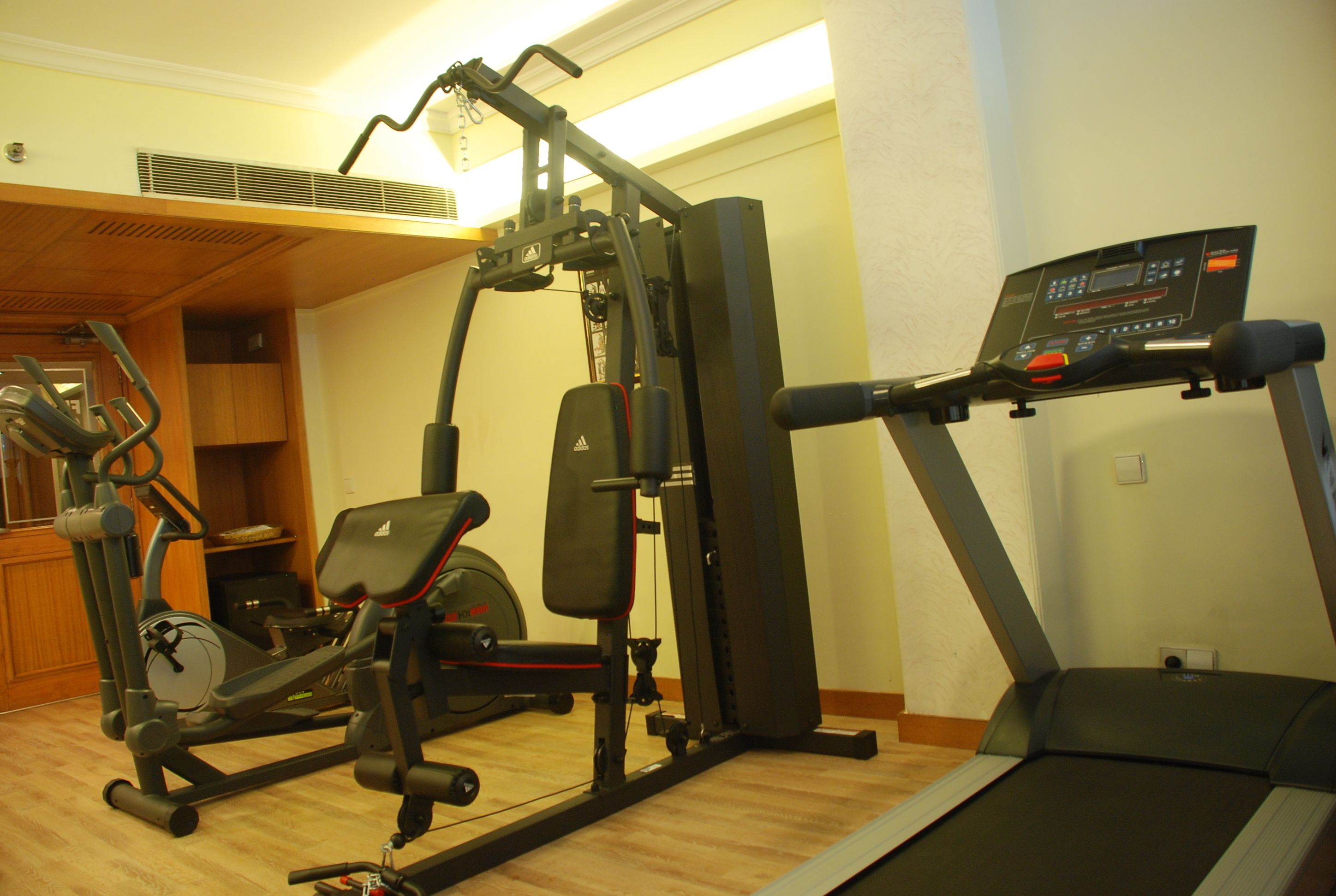 Un gimnasio en casa con cinta de correr, elíptica y máquina de pesas.