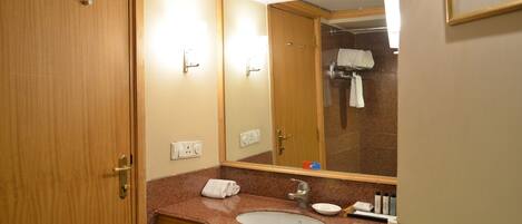 Un baño con puerta de madera, un lavabo con encimera de mármol, un espejo y una toalla colgada en la pared.