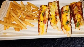 A white rectangular plate with French fries and grilled sandwiches.