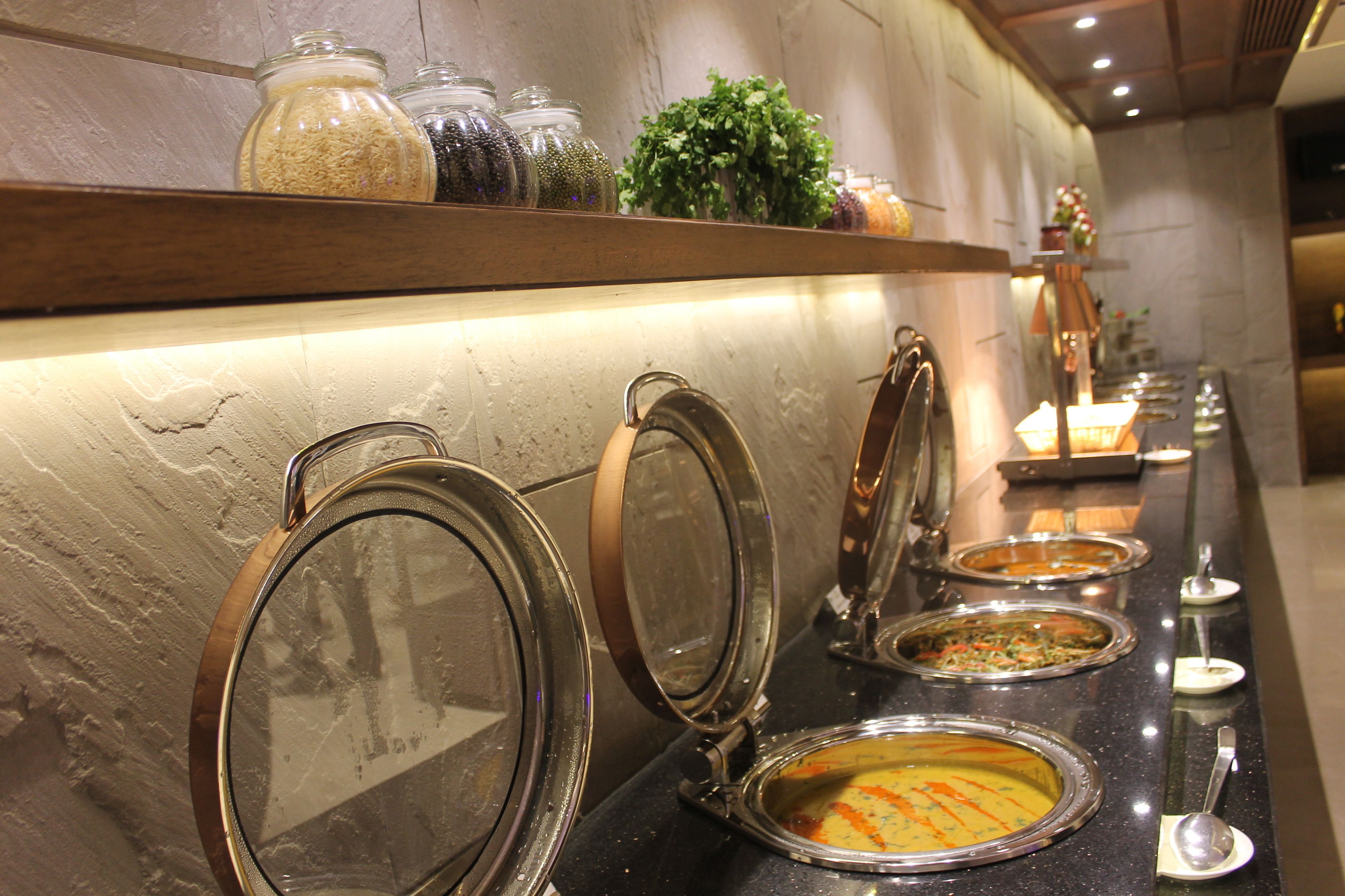 Una barra de buffet con diferentes recipientes de comida y utensilios.