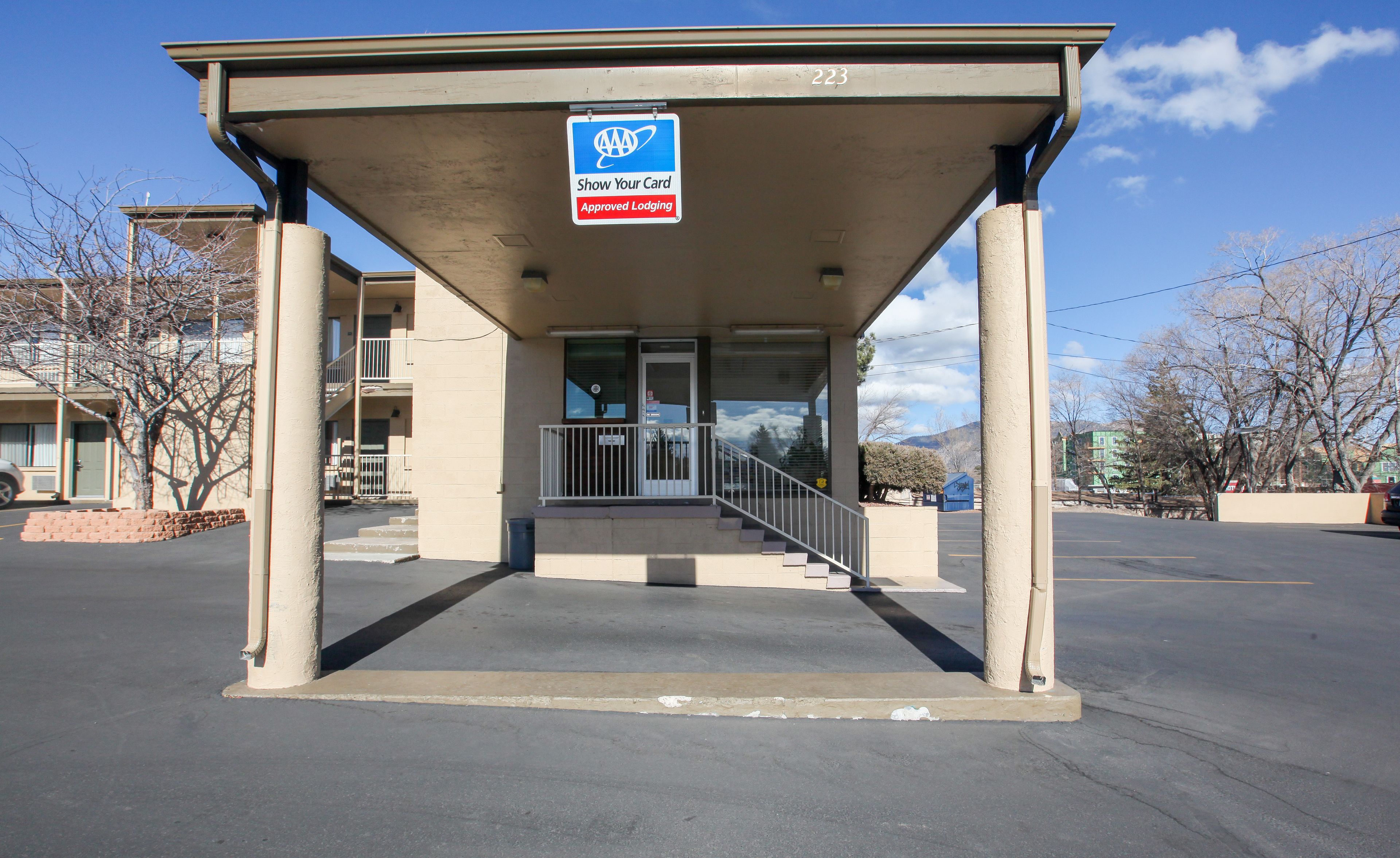 A building with a covered entrance, a sign indicating approved lodging, and a clear sky.