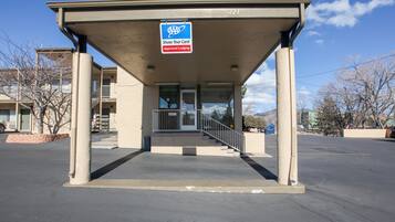 A building with a covered entrance, a sign indicating approved lodging, and a clear sky.